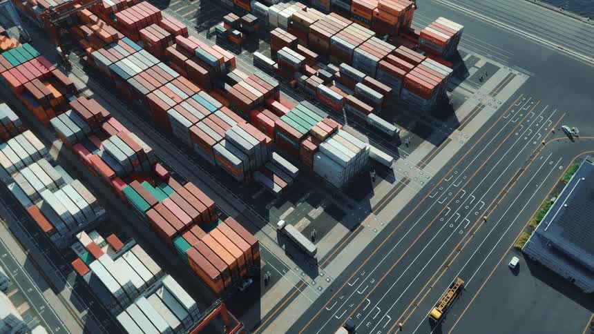 Trucks driving between rows of cargo containers in a large shipping container depot
