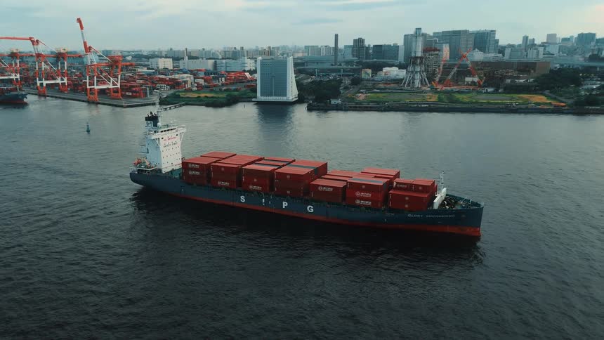 A cargo boat full of shipping containers leaving port