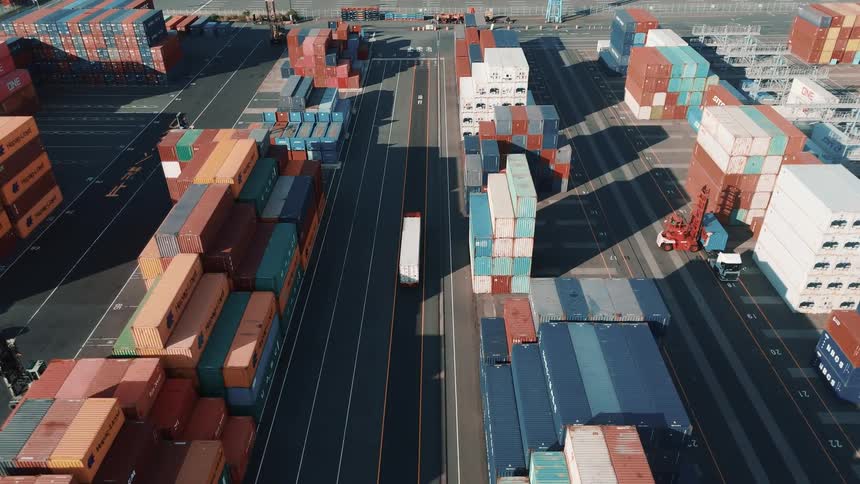 Truck traveling through a logistics port with containers