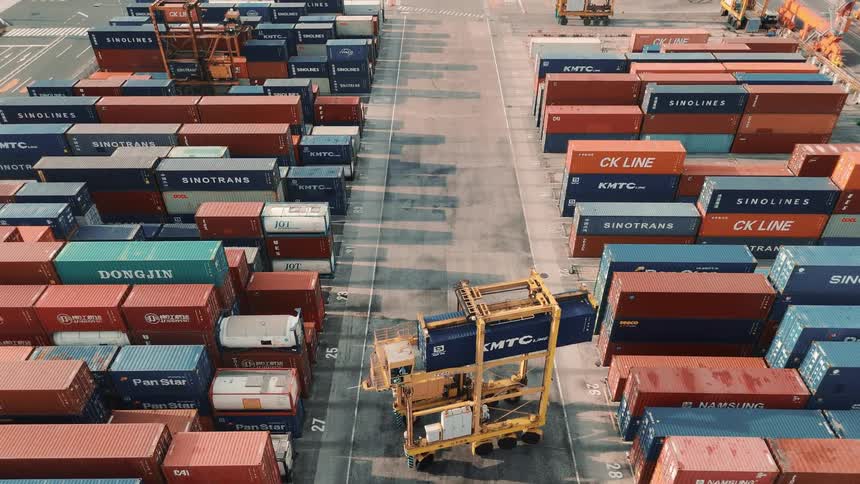 Yellow forklift moves a blue container between organized rows in the terminal