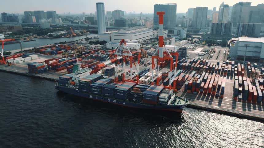 A crane loading shipping containers from a depot to a cargo boat