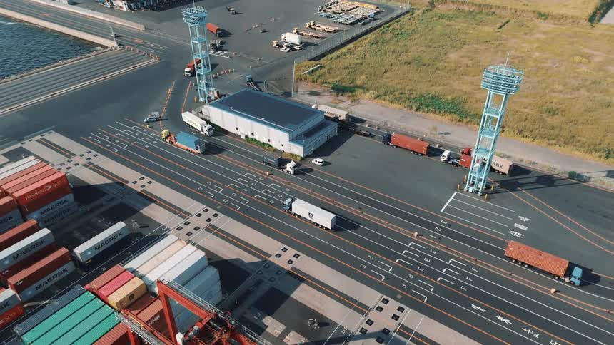 Cargo trucks driving around a container yard outdoors during day time
