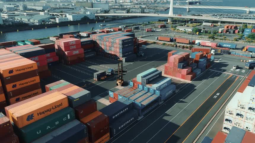 Stacks of multicolored containers organized in a port area near the water