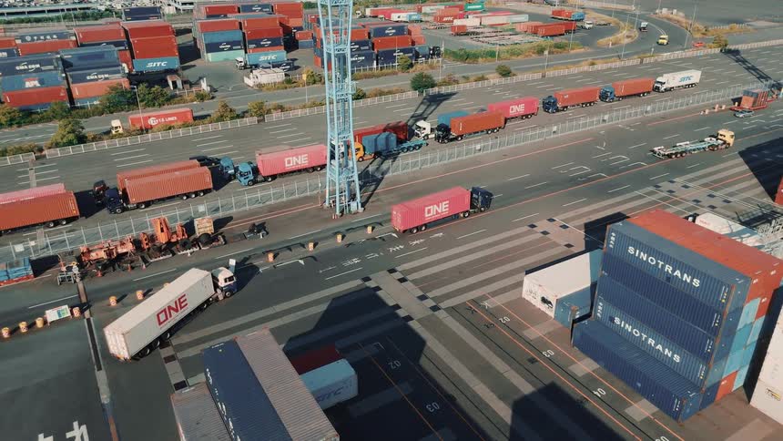 Cargo trucks driving inside a large shipping container depot