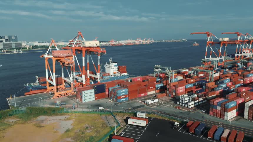 A bustling seaport at midday lined with towering stacks of colorful cargo containers and dominated by massive cranes in the harbor a cargo ship sits docked its deck loaded with neatly arranged containers