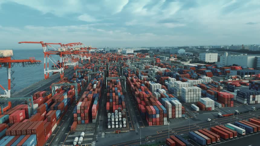A seaport is filled with stacked containers ready for transportation with cranes positioned nearby