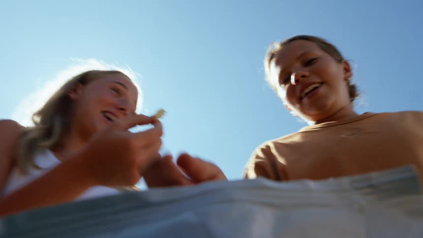 A group of people is seen from a low angle chewing food and speaking with each other