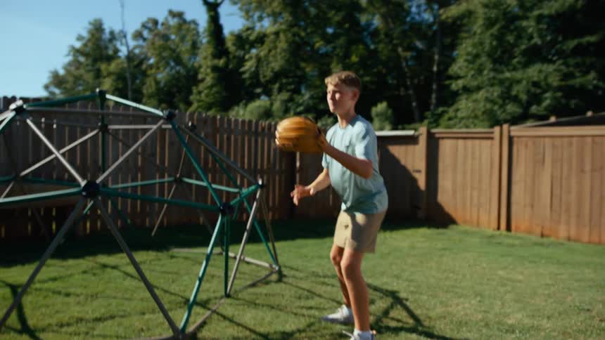 A boy is playing catch with a baseball glove in a backyard