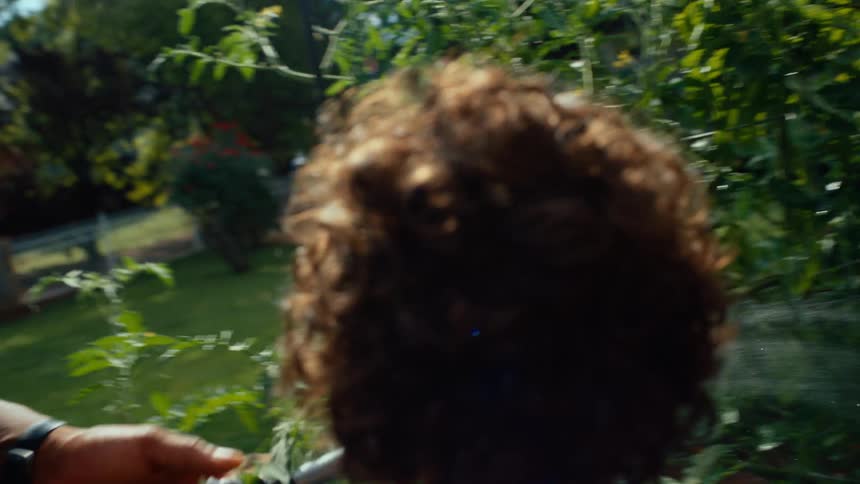 A father and his son irrigating plants in a backyard on a sunny day
