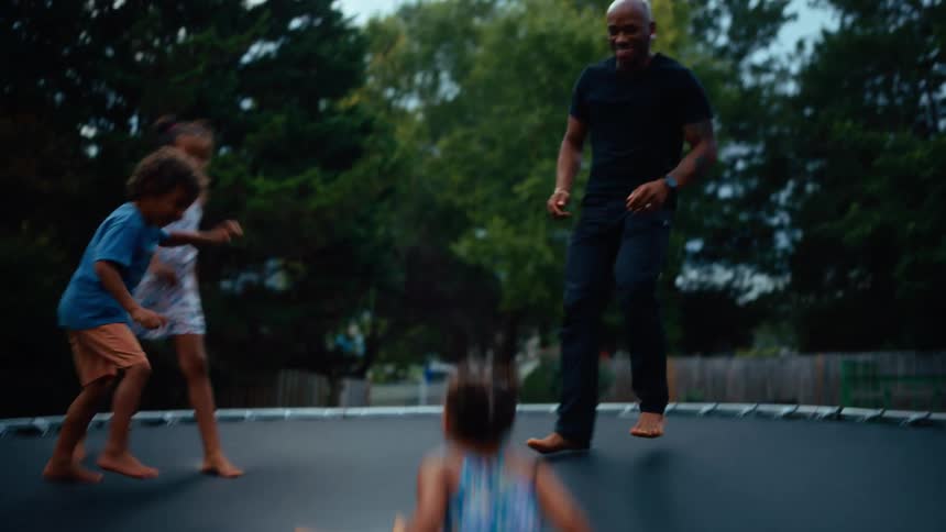 The children bounce on the trampoline with their parents