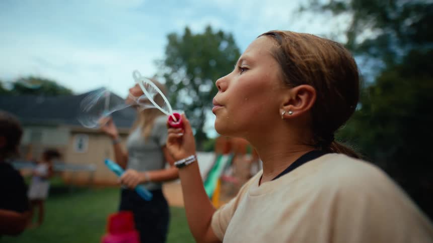 A group of people playing with bubble toys in a backyard on a sunny day