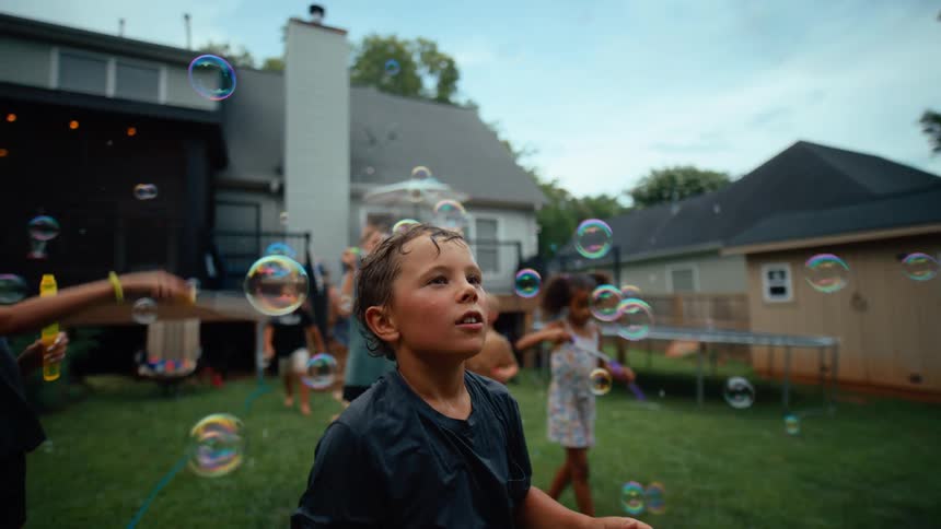 Children swat at the bubbles in the yard