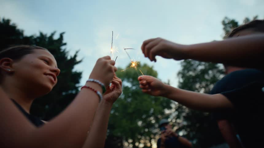 A group of people stand outside and hold sparklers