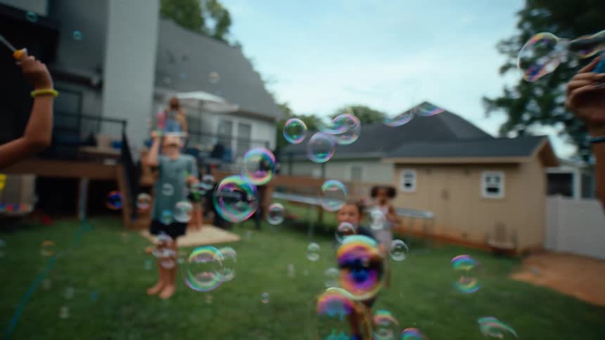 Children and adults play with bubbles and enjoy a backyard gathering