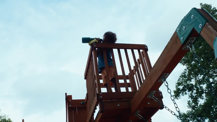 Male biracial child on a playground playing with a monocular scope outdoors during day time