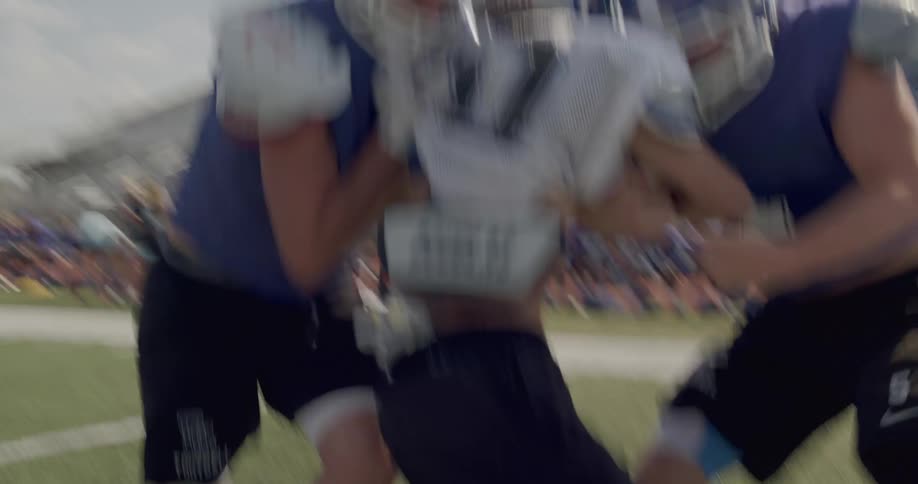 The video shows a football practice with two distinct lines of players in the foreground three playerstwo in blue jerseys and one in a white jersey with the name douglas on itare running toward the left in the background a stationary line of playe