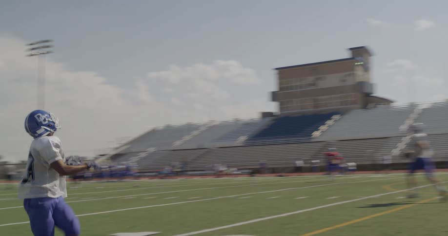 Football player catches a pass during a training session on a football field on a cloudy day