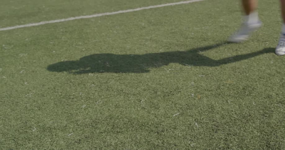 Shadow shows a football player throwing the football on a summer day