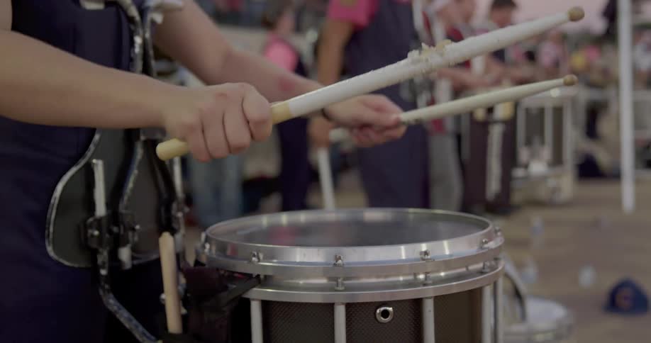 Band drummers standing outdoors play their instruments