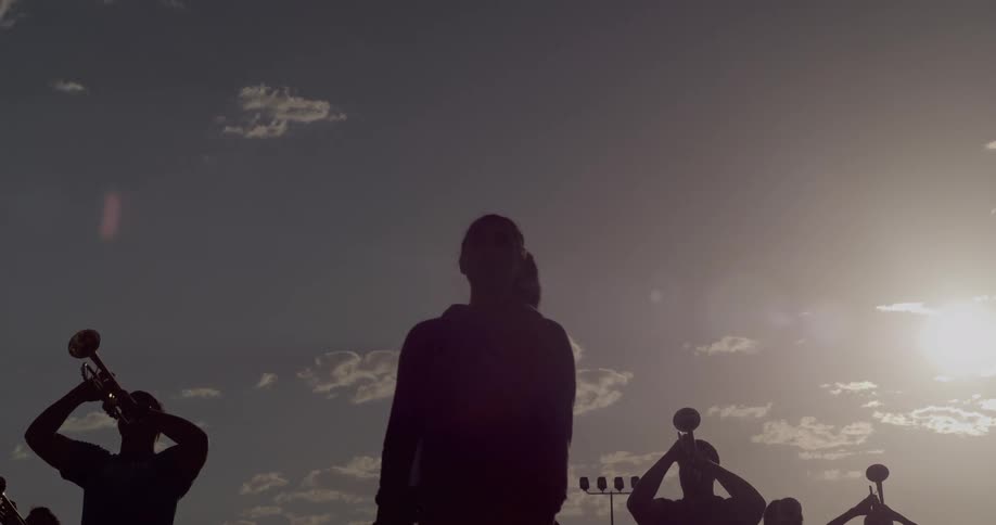 Sunlight casts the members of a brass band playing outside into silhouette