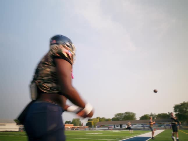 An american football player tossed the ball on the pitch wearing a jersey and helmet