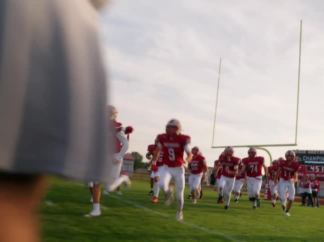 American football team entering the field with cheerleaders cheering