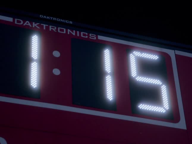 A bright red scoreboard shows the time counting down from one minute and fifteen seconds with the numbers in a digital dot matrix style
