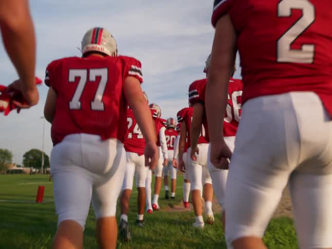 American football team entering a grass field