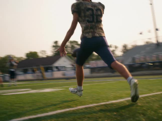 A football player punting a football during practice on a field