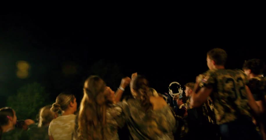 American football team celebrating outdoors at night