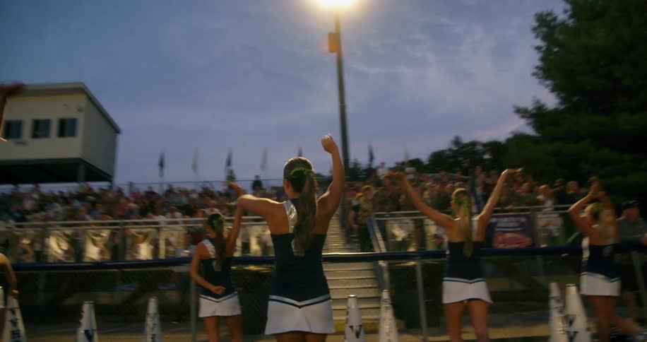 Group of cheerleaders dancing in front of a crowd in the stands