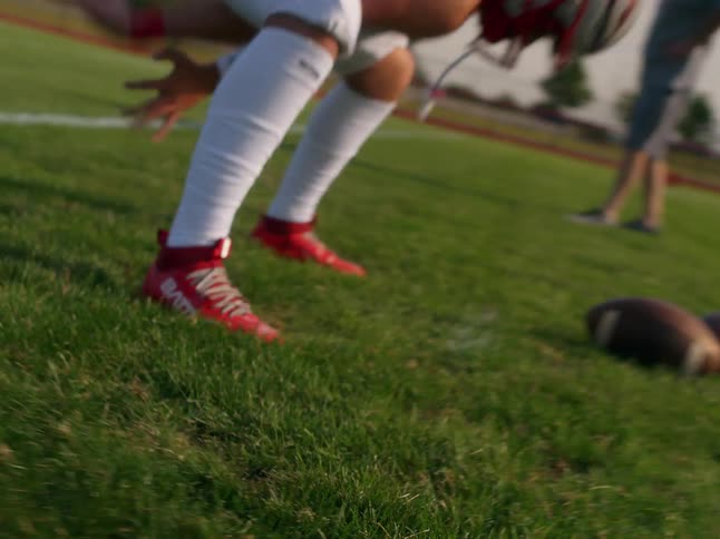 The video shows a lowangle shot of a persons legs walking on a gravel or asphalt surface with painted lines a white line is visible in the foreground another white line is visible in the midground running parallel to the first line