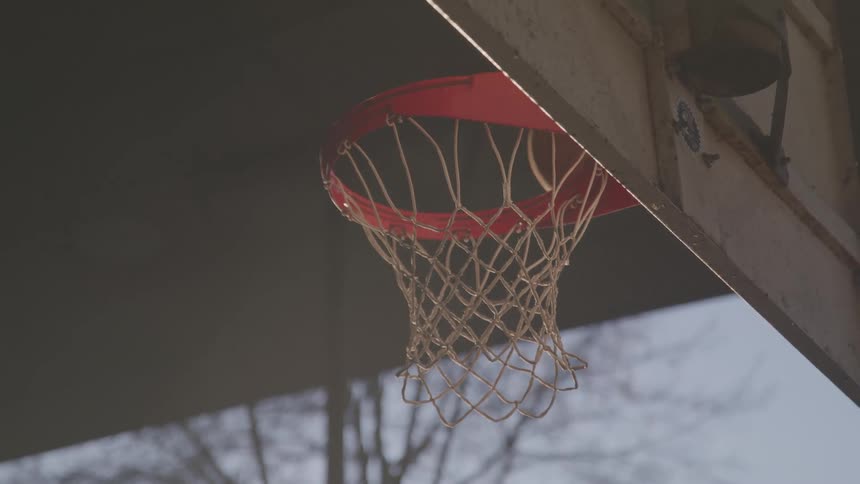 A basketball bounces past the hoop on an outdoor court
