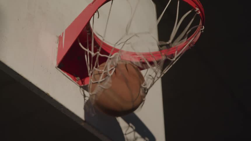 A basketball drops through the hoop on a court during a game