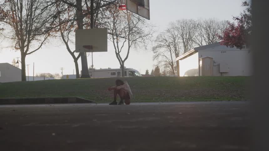 Person sitting on a ball on a basketball court