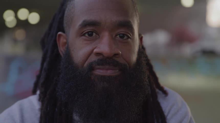 Young black man with long black beard and long braided hair smiling