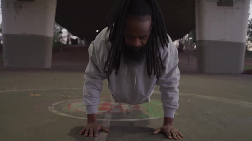 A man stretches while exercising on an outdoor court