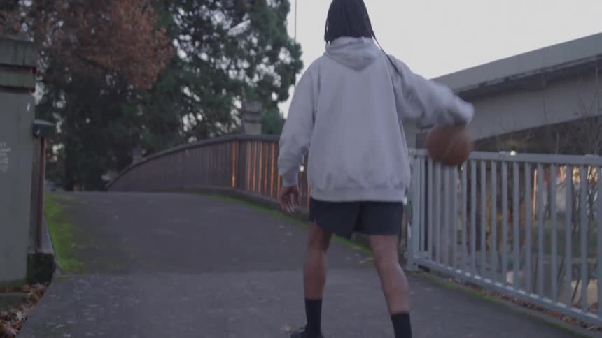 The man bounces his basketball down the path