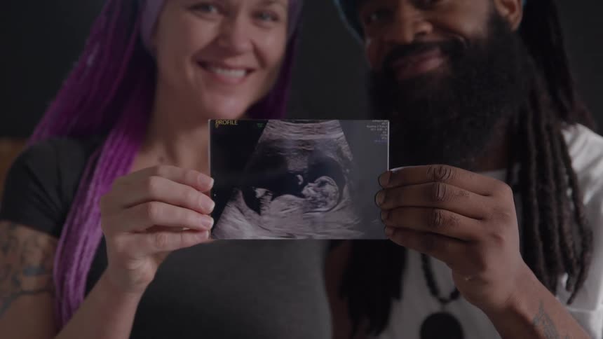 Couple holding a photograph of a pregnancy scan