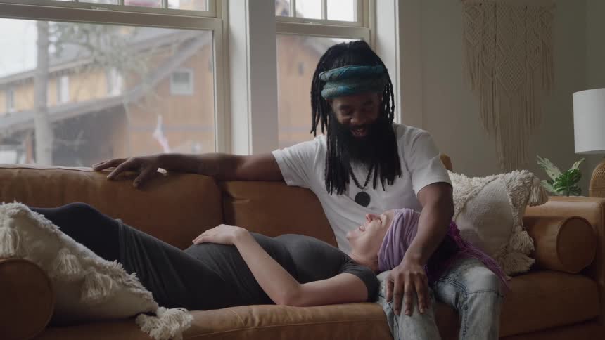 A pregnant woman rests in a mans lap