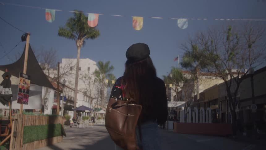 Woman with a backpack walks along a street decorated with colorful flags
