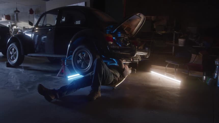 Man lying on a creeper works under a beetle inside the workshop