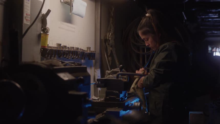 Woman focuses on cleaning a tool at the workshop bench