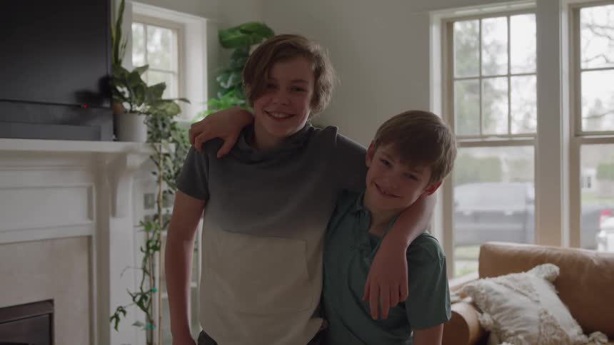 Two smiling brothers hug in the living room