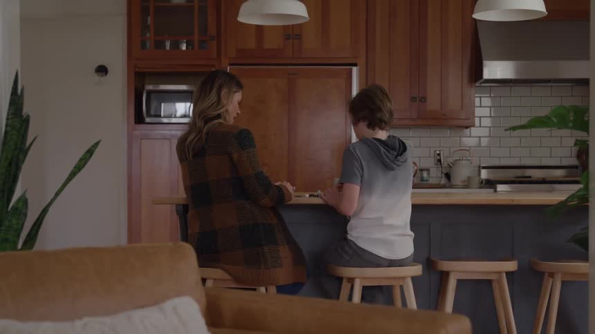Mother and son sit on stools talking in the kitchen