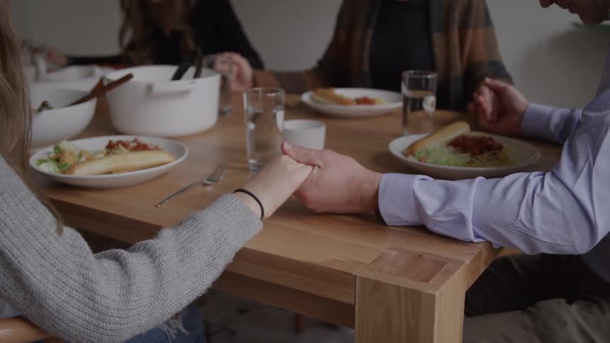 People holding hands around the table before the meal