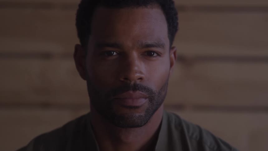 Closeup of a man looking at the camera against a wooden backdrop