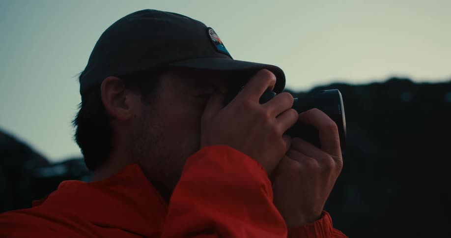 A man takes a photo with his camera outdoors at dusk