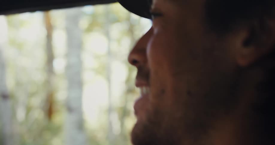 A man inside a car driving and smiling happily