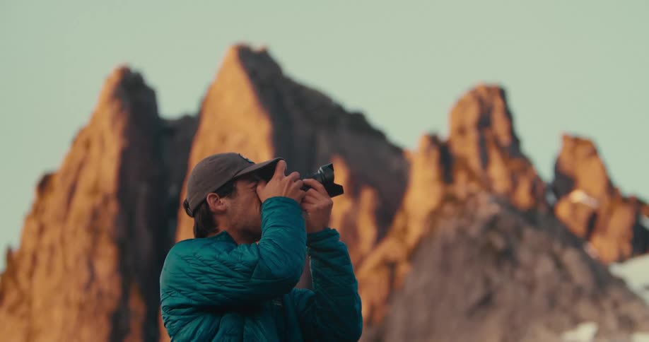 Man in a blue jacket captures the sunlit mountains